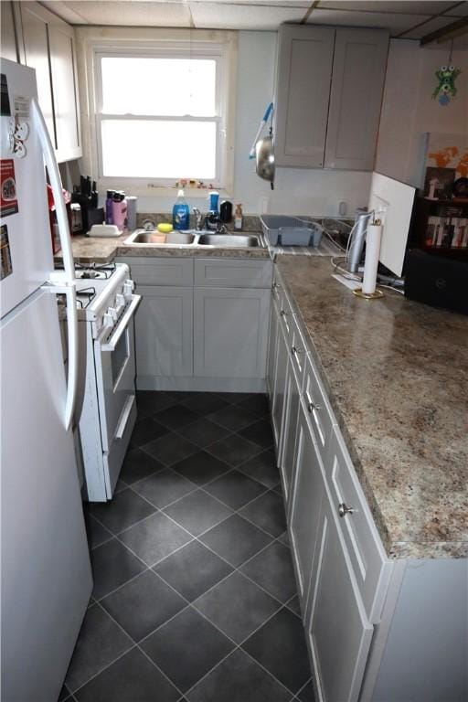 kitchen with white appliances, gray cabinets, light stone counters, and sink