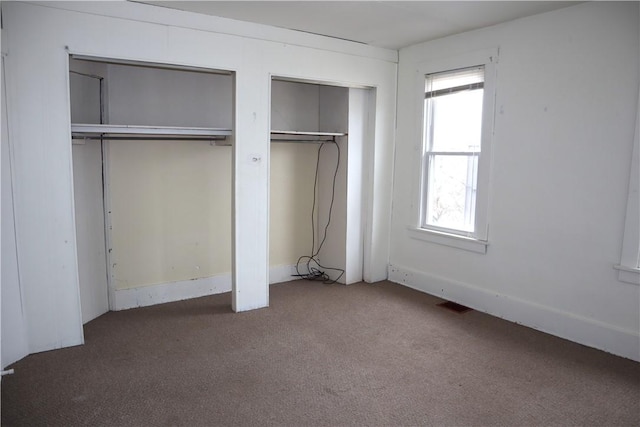 unfurnished bedroom featuring carpet floors and two closets