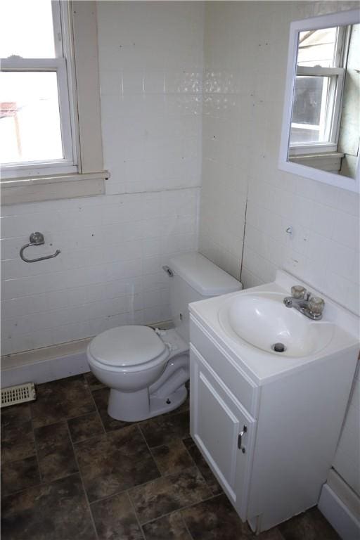 bathroom featuring a wealth of natural light, vanity, tile walls, and toilet