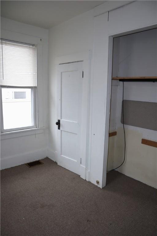 unfurnished bedroom with dark colored carpet and a closet