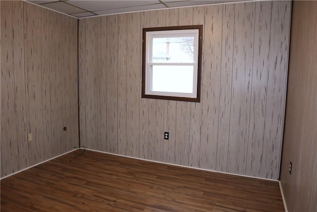 unfurnished room with dark hardwood / wood-style flooring and wooden walls