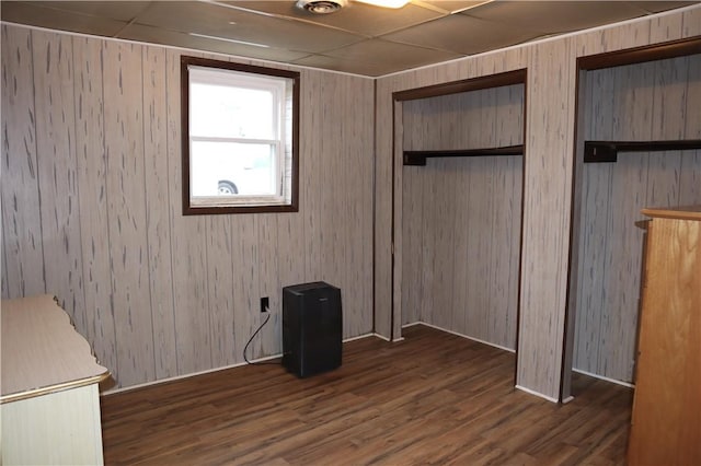 unfurnished bedroom featuring wood walls and dark wood-type flooring