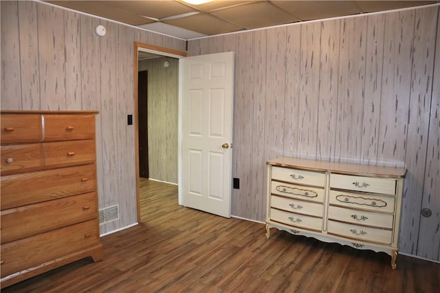 unfurnished bedroom with wood walls and dark wood-type flooring