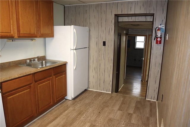 kitchen with white fridge, light hardwood / wood-style flooring, and sink