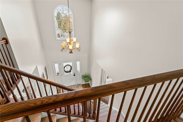 entryway featuring carpet, a chandelier, and a high ceiling