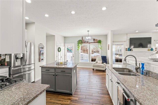 kitchen featuring sink, gray cabinets, decorative light fixtures, light stone counters, and stainless steel appliances