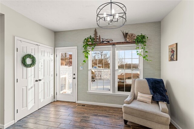 sitting room with wood-type flooring, a wealth of natural light, and an inviting chandelier