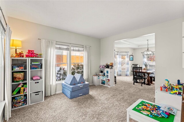 playroom featuring carpet, a healthy amount of sunlight, and an inviting chandelier