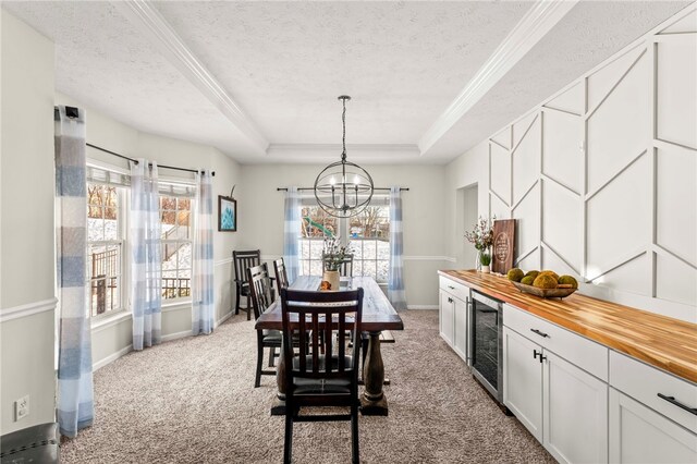 carpeted dining room with a tray ceiling, wine cooler, a textured ceiling, and a notable chandelier