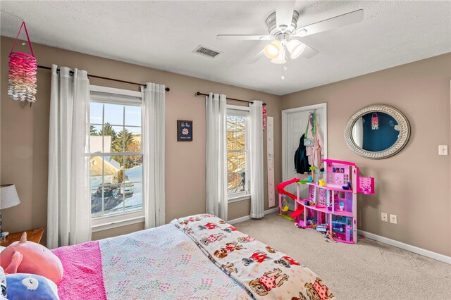 bedroom with ceiling fan, light carpet, and a textured ceiling