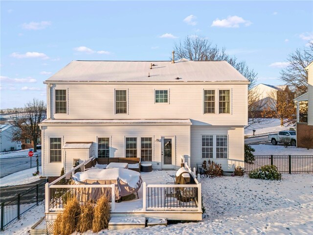 snow covered back of property with a deck