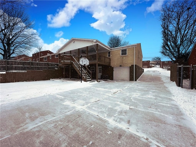 snow covered rear of property featuring a deck and a garage