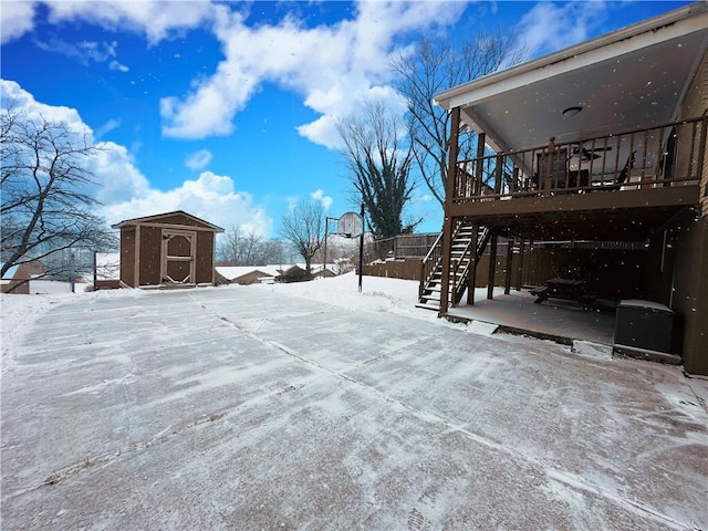 yard layered in snow with a shed and a wooden deck