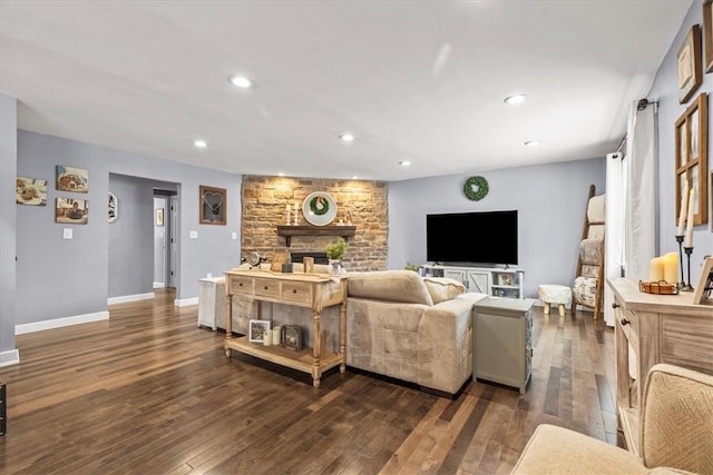 living room with a stone fireplace and dark hardwood / wood-style flooring