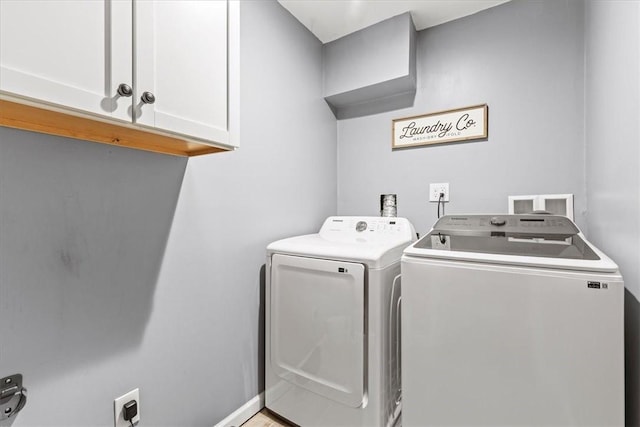 clothes washing area featuring washing machine and dryer and cabinets