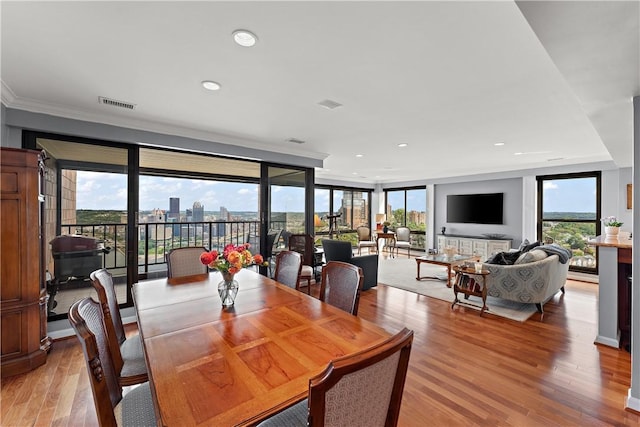 dining space with a wall of windows, light wood-type flooring, and ornamental molding