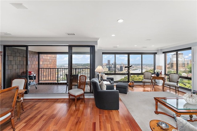 living room with hardwood / wood-style flooring, ornamental molding, and a healthy amount of sunlight