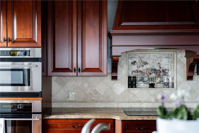 kitchen with stainless steel double oven, light stone countertops, black electric stovetop, and decorative backsplash