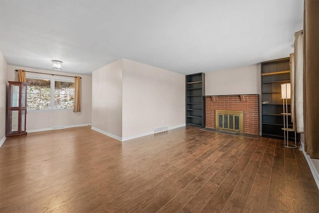 unfurnished living room with dark hardwood / wood-style floors and a brick fireplace