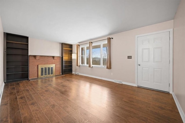 unfurnished living room featuring dark hardwood / wood-style floors and a brick fireplace