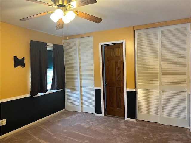 unfurnished bedroom featuring carpet, ceiling fan, and multiple closets