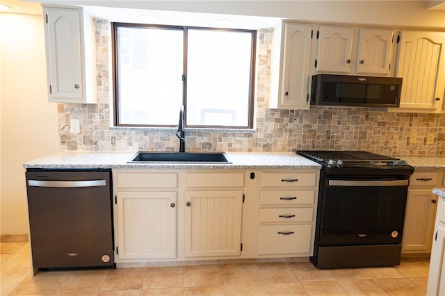 kitchen featuring light stone counters, light tile patterned flooring, a sink, decorative backsplash, and black appliances