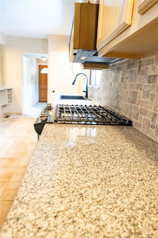 kitchen featuring a sink, light stone countertops, and backsplash