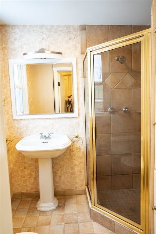 bathroom with wallpapered walls, a shower stall, and baseboards