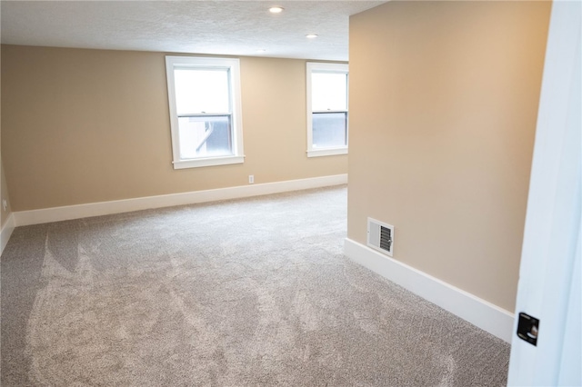 unfurnished room featuring baseboards, visible vents, carpet floors, and a textured ceiling