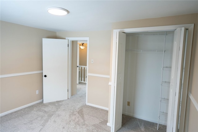 unfurnished bedroom featuring a closet, baseboards, and light colored carpet