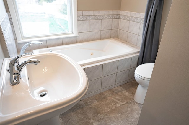 bathroom featuring a sink, a garden tub, and toilet