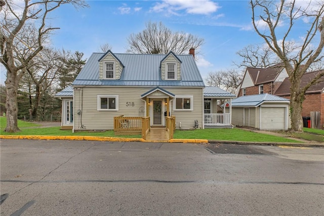 new england style home with an outbuilding, a garage, and a front yard