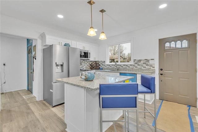 kitchen with light wood finished floors, decorative backsplash, white cabinetry, and appliances with stainless steel finishes