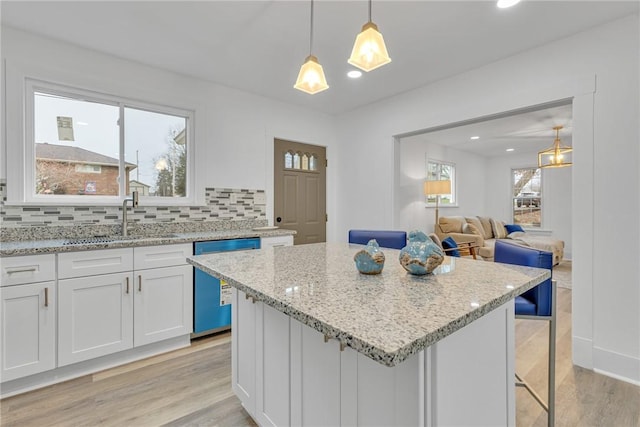 kitchen featuring light wood-style flooring, a sink, white cabinetry, dishwasher, and tasteful backsplash