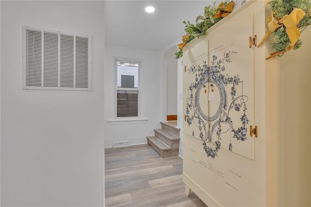 hallway with light wood-style flooring, stairs, and visible vents