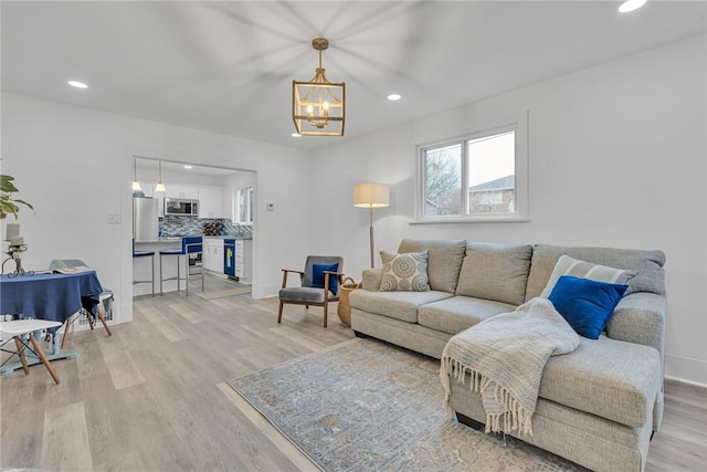 living area with light wood-style floors, recessed lighting, a chandelier, and baseboards