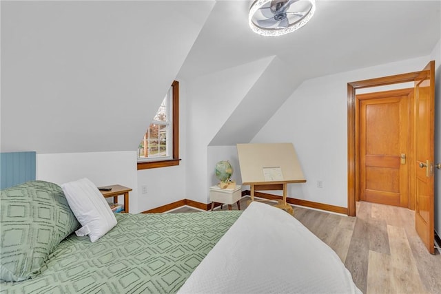 bedroom with lofted ceiling, baseboards, and wood finished floors