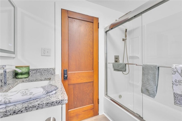 bathroom featuring combined bath / shower with glass door and vanity