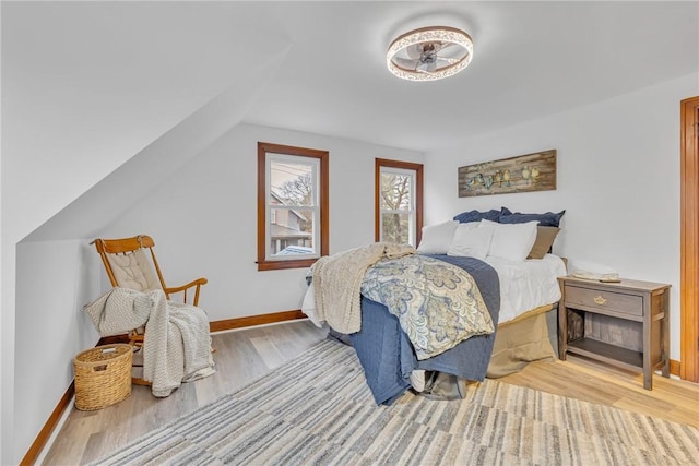 bedroom with baseboards, vaulted ceiling, and wood finished floors