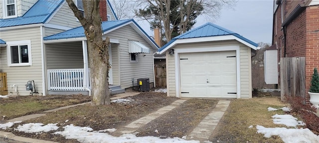 view of side of property with driveway, a porch, metal roof, and an outdoor structure