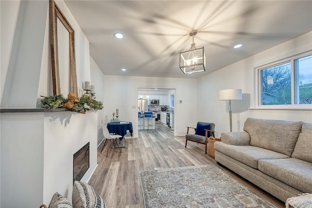 living room with a chandelier, light wood-style flooring, and recessed lighting