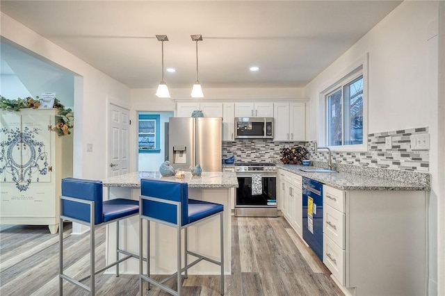kitchen with a kitchen bar, stainless steel appliances, light wood-type flooring, and a sink