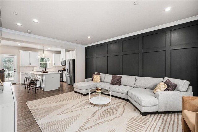 living room featuring sink, ornamental molding, and light hardwood / wood-style flooring