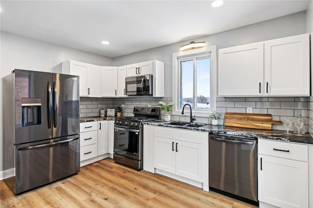 kitchen with dark stone counters, sink, white cabinets, and stainless steel appliances