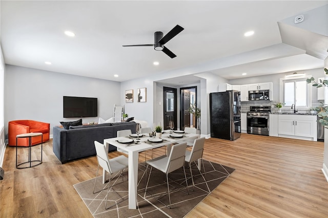 dining area featuring ceiling fan, light wood-type flooring, and sink