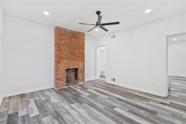 unfurnished living room featuring ceiling fan, light wood-type flooring, and a brick fireplace