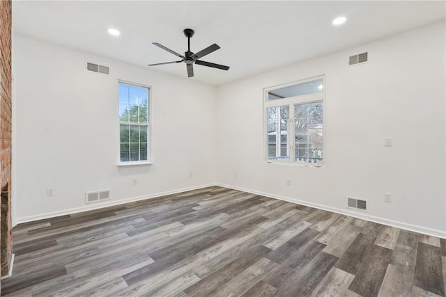 spare room featuring dark hardwood / wood-style floors, a brick fireplace, and ceiling fan