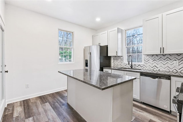 kitchen featuring sink, a kitchen island, dark stone counters, white cabinets, and appliances with stainless steel finishes