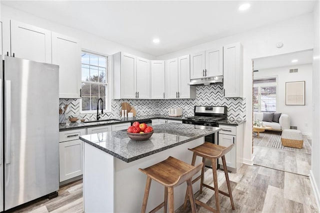 kitchen with appliances with stainless steel finishes, light wood-type flooring, white cabinetry, and sink