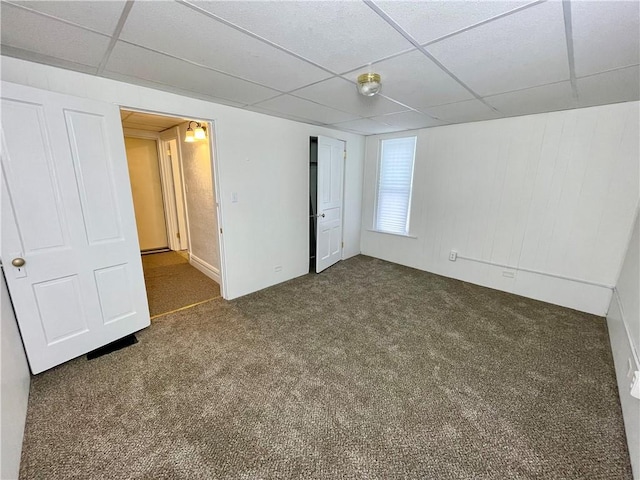 unfurnished bedroom with dark colored carpet and a paneled ceiling